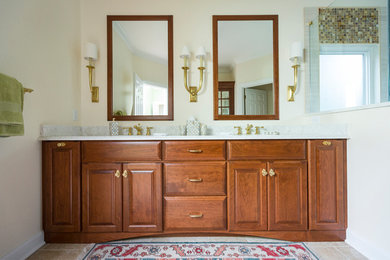 Design ideas for a mid-sized traditional master bathroom in Cincinnati with raised-panel cabinets, medium wood cabinets, a corner shower, a one-piece toilet, beige tile, porcelain tile, beige walls, porcelain floors, an undermount sink, quartzite benchtops, beige floor and a hinged shower door.