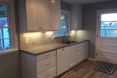 This is an example of a small transitional galley eat-in kitchen in Raleigh with an undermount sink, flat-panel cabinets, white cabinets, granite benchtops, grey splashback, subway tile splashback and white appliances.