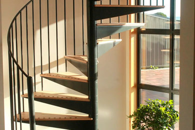 Photo of a small modern wood spiral staircase in Other with open risers.