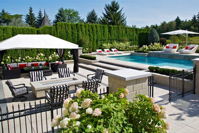 Photo of a mid-sized transitional backyard custom-shaped pool in Montreal with a water feature and concrete slab.
