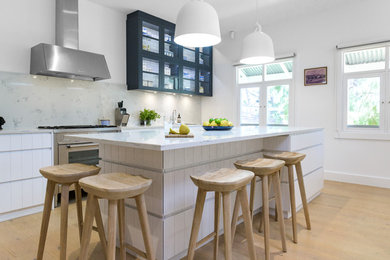 Inspiration for a contemporary galley eat-in kitchen in Adelaide with flat-panel cabinets, white cabinets, grey splashback, glass sheet splashback, stainless steel appliances, light hardwood floors, with island, beige floor and grey benchtop.