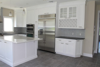 Example of a trendy porcelain tile kitchen design in New York with shaker cabinets, white cabinets, glass tile backsplash, stainless steel appliances and an island