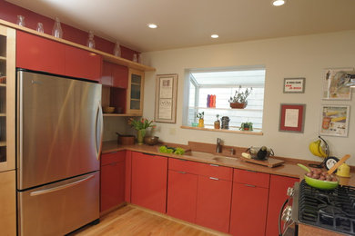 Example of a mid-sized minimalist u-shaped light wood floor eat-in kitchen design in Denver with an undermount sink, flat-panel cabinets, orange cabinets, granite countertops, orange backsplash, stone slab backsplash, stainless steel appliances and a peninsula