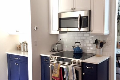 Example of a transitional medium tone wood floor and brown floor kitchen design in Denver with shaker cabinets, white cabinets, quartzite countertops, white backsplash, subway tile backsplash and stainless steel appliances