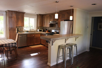 Eat-in kitchen - mid-sized contemporary l-shaped medium tone wood floor eat-in kitchen idea in Boise with an undermount sink, shaker cabinets, medium tone wood cabinets, concrete countertops, multicolored backsplash, glass tile backsplash, stainless steel appliances and a peninsula