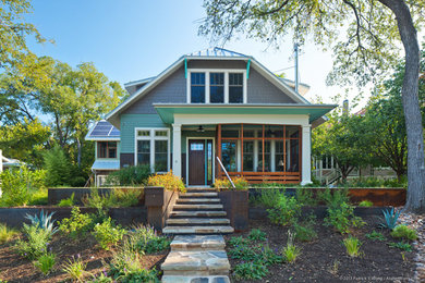 Inspiration for a transitional two-storey green house exterior in Austin with concrete fiberboard siding, a clipped gable roof and a metal roof.