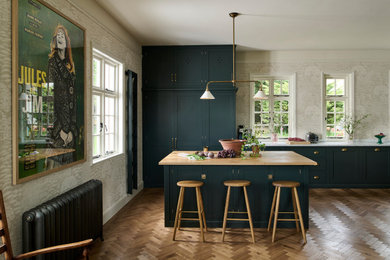 This is an example of a large traditional kitchen/diner in Other with a belfast sink, shaker cabinets, green cabinets, marble worktops, green splashback, ceramic splashback, medium hardwood flooring, an island and brown floors.