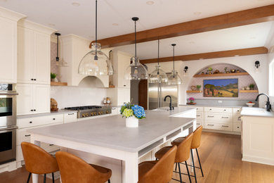 Example of a large transitional medium tone wood floor and exposed beam eat-in kitchen design in Other with white backsplash, stainless steel appliances and an island