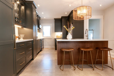 Enclosed kitchen - mid-sized transitional galley porcelain tile and gray floor enclosed kitchen idea in Toronto with an undermount sink, shaker cabinets, green cabinets, quartz countertops, white backsplash, ceramic backsplash, stainless steel appliances, an island and white countertops