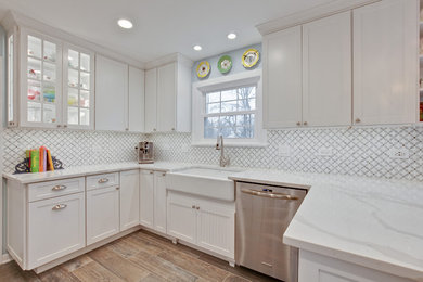 Inspiration for a mid-sized transitional u-shaped light wood floor and brown floor eat-in kitchen remodel in Chicago with a farmhouse sink, shaker cabinets, white cabinets, marble countertops, white backsplash, stainless steel appliances, a peninsula and white countertops