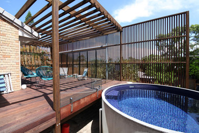 Imagen de terraza planta baja urbana de tamaño medio con privacidad, pérgola y barandilla de madera