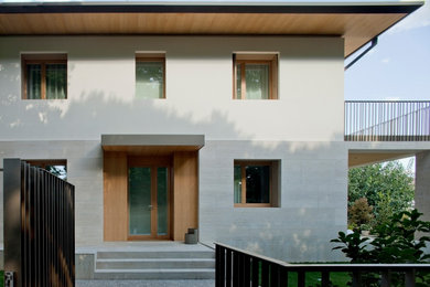 Foto della villa beige moderna a tre piani di medie dimensioni con rivestimento in pietra, tetto a padiglione, copertura in metallo o lamiera, tetto grigio, pannelli sovrapposti e abbinamento di colori