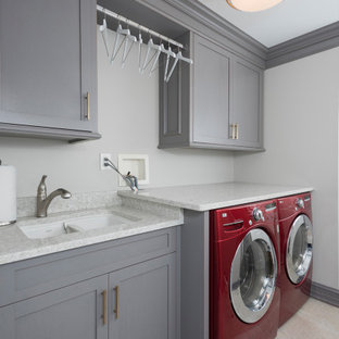 ニューヨークの中サイズのモダンスタイルのおしゃれなランドリークローゼット (ダブルシンク、落し込みパネル扉のキャビネット、白いキャビネット、御影石カウンター、ベージュの壁、ラミネートの床、左右配置の洗濯機・乾燥機、グレーの床、白いキッチンカウンター) の写真