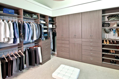 This is an example of a large contemporary men's walk-in wardrobe in Miami with flat-panel cabinets, medium wood cabinets and carpet.