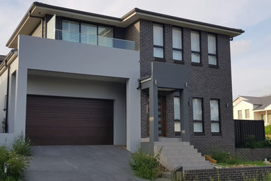 Large modern two-storey brick grey house exterior in Sydney with a hip roof and a tile roof.