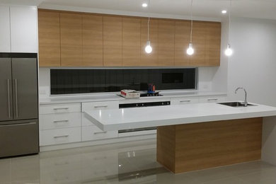 Photo of a large modern galley open plan kitchen in Adelaide with a single-bowl sink, flat-panel cabinets, white cabinets, quartz benchtops, white splashback, stainless steel appliances, ceramic floors and with island.