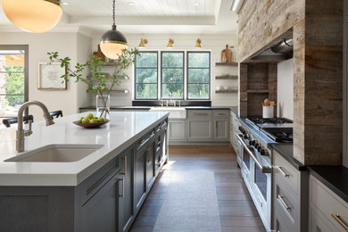 Farmhouse medium tone wood floor and shiplap ceiling kitchen photo in Other with a farmhouse sink, gray cabinets, solid surface countertops, white backsplash, stone slab backsplash, stainless steel appliances, an island and white countertops