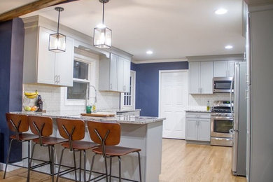 Inspiration for a mid-sized modern medium tone wood floor and brown floor eat-in kitchen remodel in Chicago with a farmhouse sink, shaker cabinets, gray cabinets, granite countertops, white backsplash, subway tile backsplash, stainless steel appliances and a peninsula