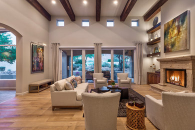 Huge open concept light wood floor and brown floor living room photo in Phoenix with gray walls, a standard fireplace, a plaster fireplace and a wall-mounted tv
