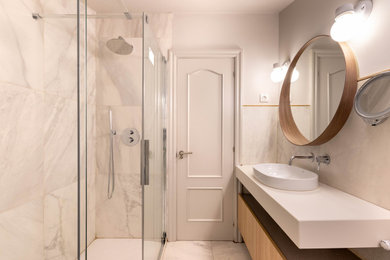 Design ideas for a mid-sized scandinavian master wet room bathroom in Bilbao with recessed-panel cabinets, white cabinets, a bidet, black and white tile, marble, white walls, ceramic floors, an integrated sink, solid surface benchtops, white floor, a sliding shower screen and white benchtops.