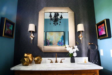 Powder room - mid-sized transitional gray tile, white tile and stone tile medium tone wood floor powder room idea in Indianapolis with medium tone wood cabinets, a one-piece toilet, blue walls, a drop-in sink and solid surface countertops