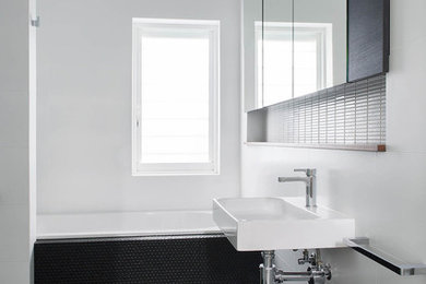 Contemporary bathroom in Perth with a drop-in tub, white tile, white walls, mosaic tile floors, a wall-mount sink and black floor.