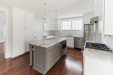 Large trendy u-shaped medium tone wood floor and brown floor eat-in kitchen photo in Baltimore with an integrated sink, shaker cabinets, white cabinets, marble countertops, white backsplash, ceramic backsplash, stainless steel appliances and an island