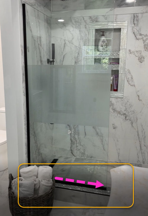 Doorless entry marble shower spilling water over the ledger