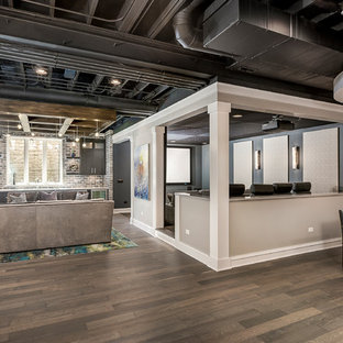 Cette photo montre une salle de cinéma tendance de taille moyenne et ouverte avec un mur gris, un sol en bois foncé, un écran de projection et un sol marron.