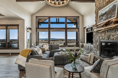 Inspiration for a rustic dark wood floor, brown floor, exposed beam and vaulted ceiling living room remodel in Other with white walls, a standard fireplace, a stone fireplace and a wall-mounted tv