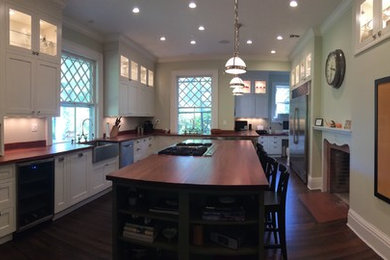 Elegant l-shaped eat-in kitchen photo in New York with flat-panel cabinets and wood countertops