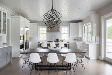 Eat-in kitchen - large transitional u-shaped medium tone wood floor eat-in kitchen idea in New York with white backsplash, an island, an undermount sink, shaker cabinets, white cabinets, stainless steel appliances and white countertops