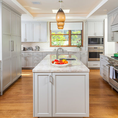 Inspiration for a mid-sized transitional u-shaped dark wood floor and brown floor enclosed kitchen remodel in Los Angeles with an undermount sink, shaker cabinets, gray cabinets, quartzite countertops, white backsplash, ceramic backsplash, stainless steel appliances, an island and gray countertops