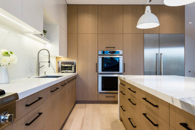 Mid-sized minimalist l-shaped light wood floor and beige floor open concept kitchen photo in Vancouver with a drop-in sink, flat-panel cabinets, white cabinets, marble countertops, white backsplash, marble backsplash, stainless steel appliances, an island and white countertops
