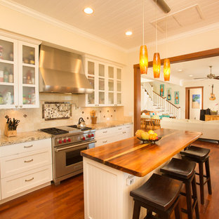 Mid-sized tropical galley kitchen pantry in Hawaii with an undermount sink, shaker cabinets, white cabinets, granite benchtops, beige splashback, stone tile splashback, stainless steel appliances, medium hardwood floors and with island.