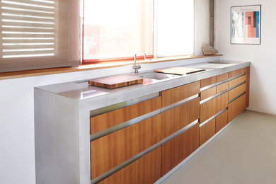Offene, Einzeilige, Große Moderne Küche ohne Insel mit Einbauwaschbecken, hellen Holzschränken, Arbeitsplatte aus Holz, Küchenrückwand in Weiß, Betonboden, grauem Boden, brauner Arbeitsplatte und flächenbündigen Schrankfronten in Sonstige