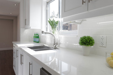 Eat-in kitchen - mid-sized transitional galley laminate floor and brown floor eat-in kitchen idea in Toronto with shaker cabinets, white cabinets, quartzite countertops, white backsplash, porcelain backsplash, stainless steel appliances, a double-bowl sink and no island