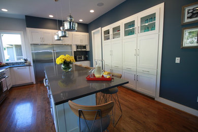 Large transitional l-shaped medium tone wood floor open concept kitchen photo in Other with an undermount sink, shaker cabinets, white cabinets, quartz countertops, blue backsplash, glass tile backsplash, stainless steel appliances and an island