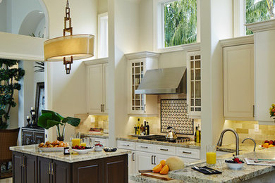 Example of a mid-sized trendy u-shaped travertine floor open concept kitchen design in Miami with an undermount sink, raised-panel cabinets, light wood cabinets, granite countertops, beige backsplash, stone tile backsplash, stainless steel appliances and an island