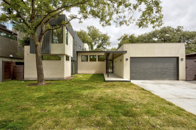 This is an example of a mid-sized modern two-storey stucco white house exterior in Austin with a white roof and board and batten siding.