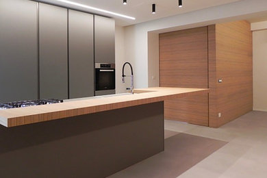 Idee per una grande cucina minimal con ante a filo, ante in legno chiaro, pavimento in gres porcellanato, pavimento grigio e top grigio