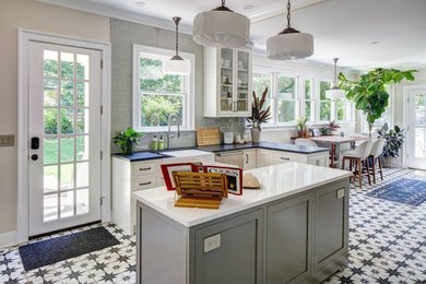 Huge country porcelain tile eat-in kitchen photo in New York with a farmhouse sink, shaker cabinets, white cabinets, quartz countertops, green backsplash, ceramic backsplash, stainless steel appliances, an island and black countertops