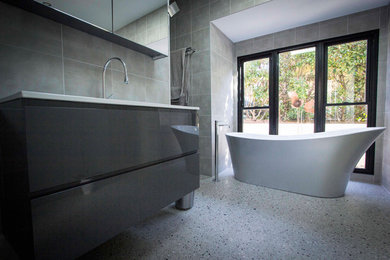 Mid-sized transitional bathroom in Sydney with raised-panel cabinets, grey cabinets, a freestanding tub, an alcove shower, a one-piece toilet, green tile, ceramic tile, green walls, concrete floors and an integrated sink.