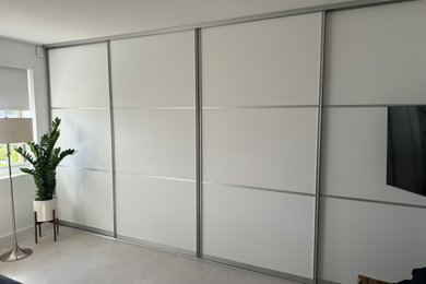 Modelo de armario y vestidor unisex moderno grande con a medida, armarios con paneles lisos, puertas de armario blancas, suelo de baldosas de cerámica y suelo beige