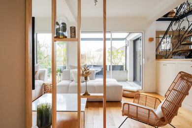 Cette photo montre un grand salon blanc et bois tendance ouvert avec un mur vert, parquet clair, aucune cheminée, un téléviseur fixé au mur, un sol marron et un escalier.