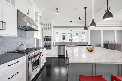 Mid-sized traditional l-shaped eat-in kitchen in Seattle with white cabinets, marble benchtops, stainless steel appliances, dark hardwood floors, with island and stone tile splashback.