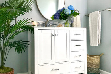 Inspiration for a mid-sized beach style master bathroom in Portland with shaker cabinets, white cabinets, a curbless shower, a one-piece toilet, blue tile, glass sheet wall, blue walls, marble floors, an undermount sink, marble benchtops, a sliding shower screen, grey benchtops, a single vanity and a freestanding vanity.