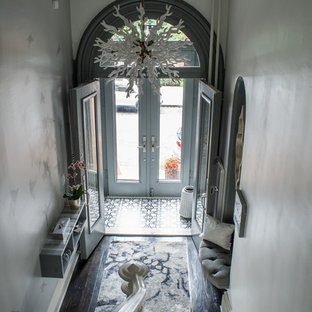 This is an example of a large eclectic foyer in New York with white walls, painted wood floors, a double front door, a black front door and black floor.