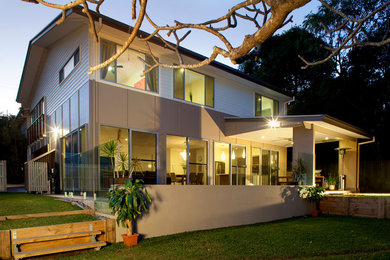 Photo of a mid-sized traditional two-storey beige exterior in Brisbane with concrete fiberboard siding and a gable roof.