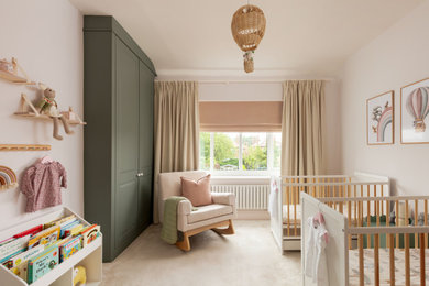 Medium sized classic nursery for girls in Other with pink walls, carpet, beige floors, wallpapered walls and feature lighting.